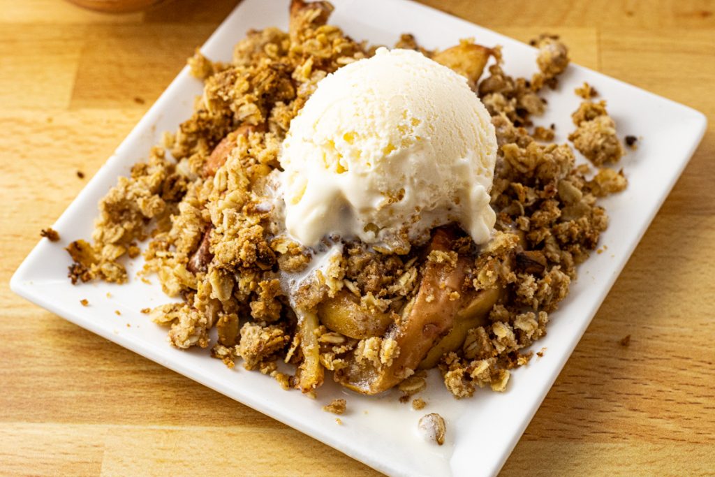 Baked apples with crisp oatmeal topping all topped with vanilla ice cream