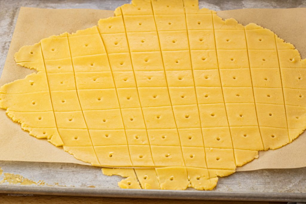 orange dough for crackers rolled out thin and sliced into squares with a small hole in the center