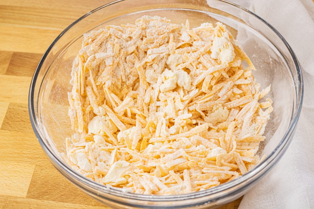 cheese and butter covered in flour in a mixing bowl