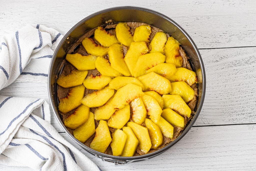 fresh peaches sliced in a round pan to make an upside down peach cake