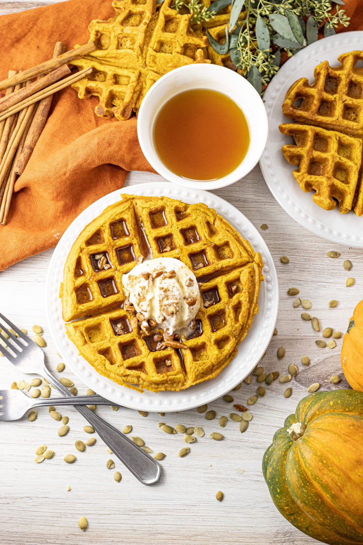 pumpkin waffles on a white plate topped with whipped cream