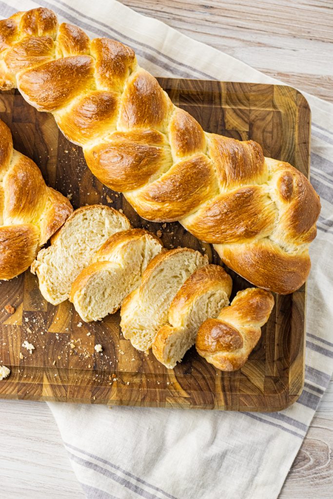 two braided loaves of bread on a wooden cutting board