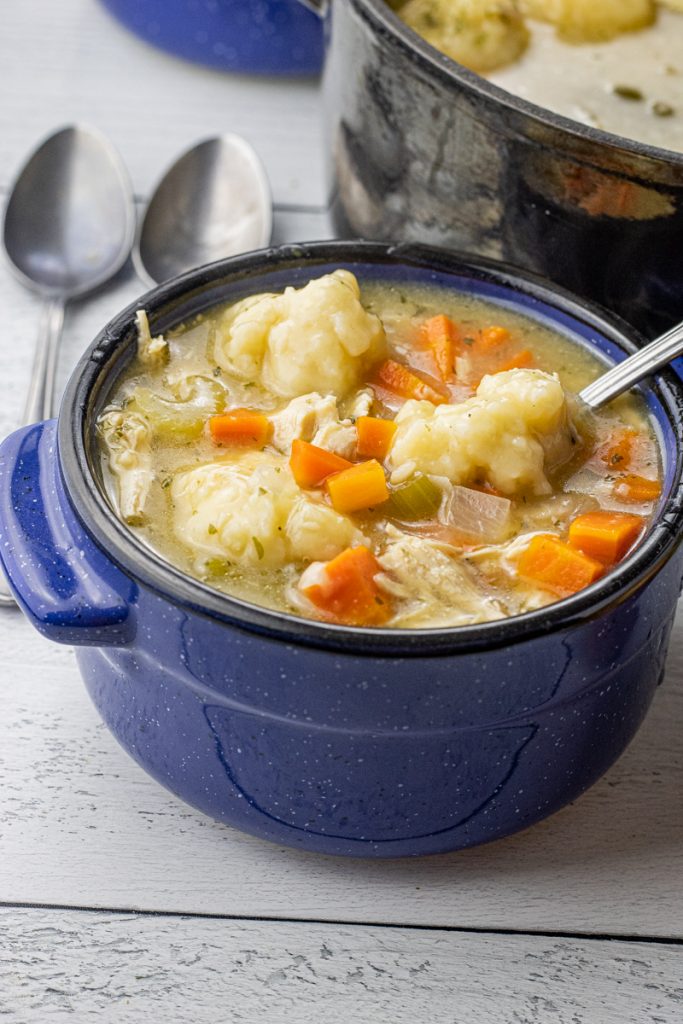 big blue bowl of chicken soup with dumplings