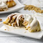 cinnamon roll cut in half on a white plate