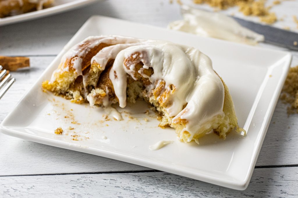 half of a cinnamon roll on a white plate