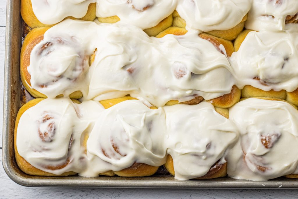 frosted cinnamon rolls on a baking sheet