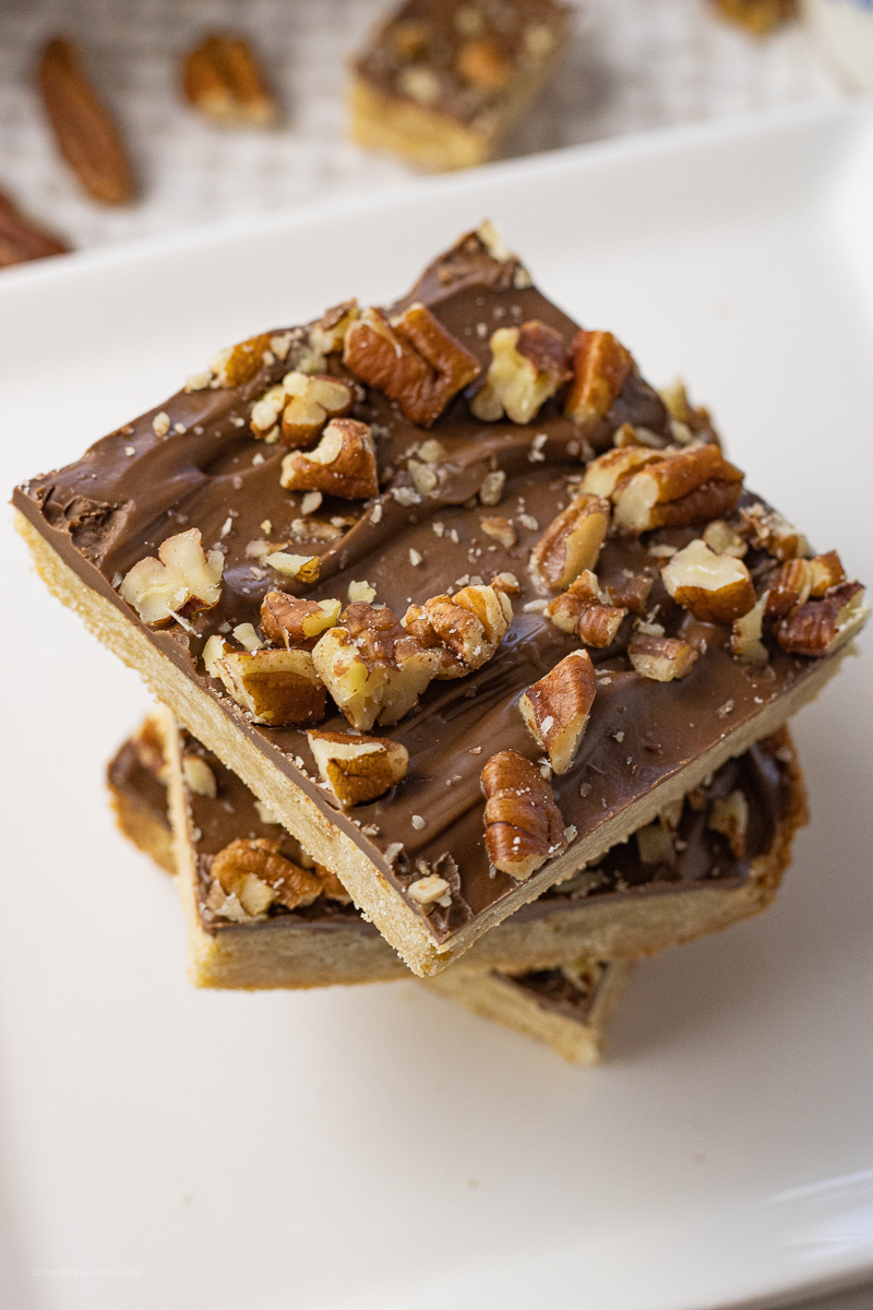 stacked shortbread bars topped with chocolate and pecans
