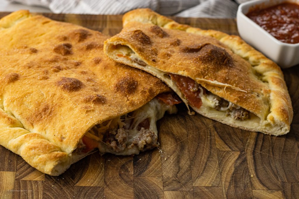 golden brown calzone cut in half with cheese and toppings coming out