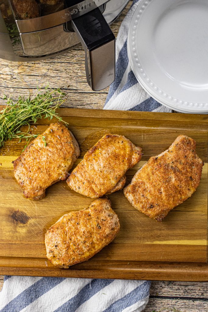 cooked pork chops on a wooden cutting board