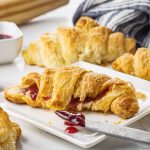 buttery croissant on a white plate with berry jam