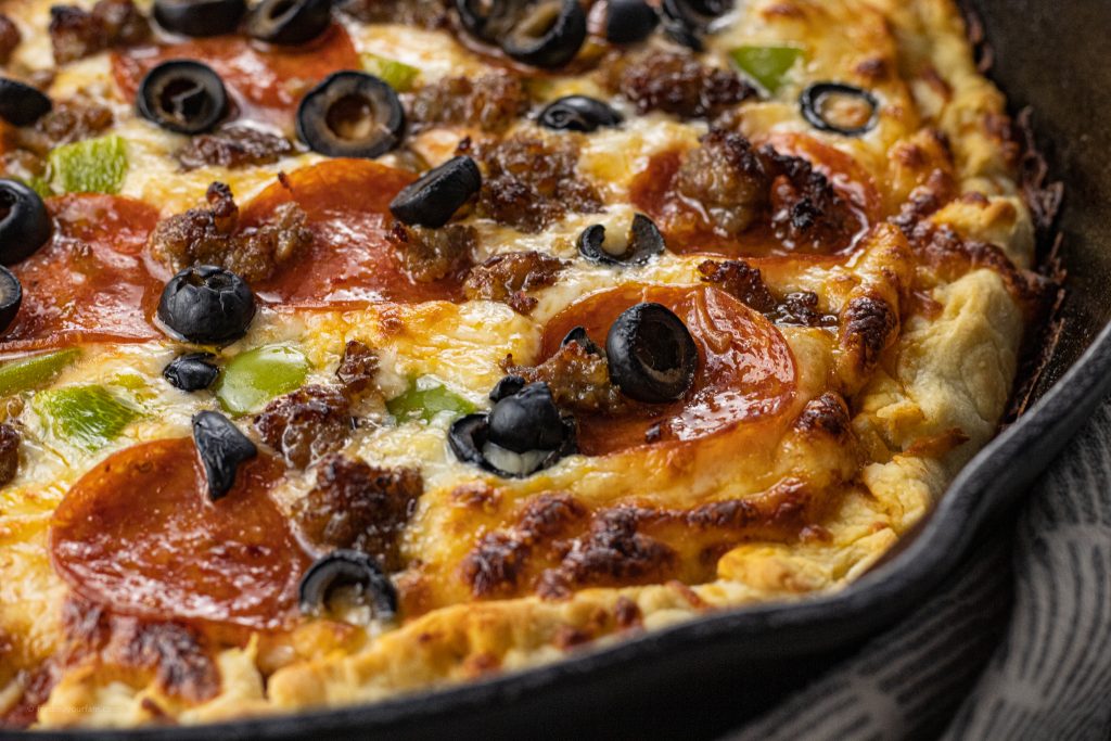 pizza cooked on cast iron skillet with olives, pepperoni, green peppers and sausage
