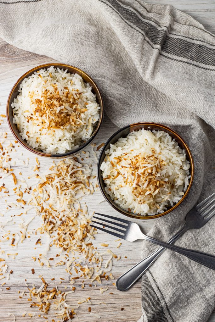 two small brown bowls of coconut rice topped with browned coconut
