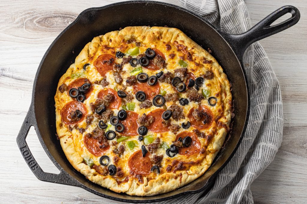 pepperoni pizza with sausage and black olives baked in a cast iron skillet