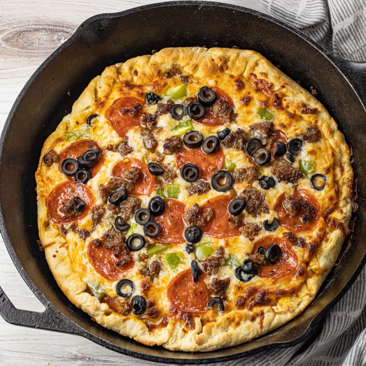 lodge cast iron pizza topped with pepperoni, sausage and olives