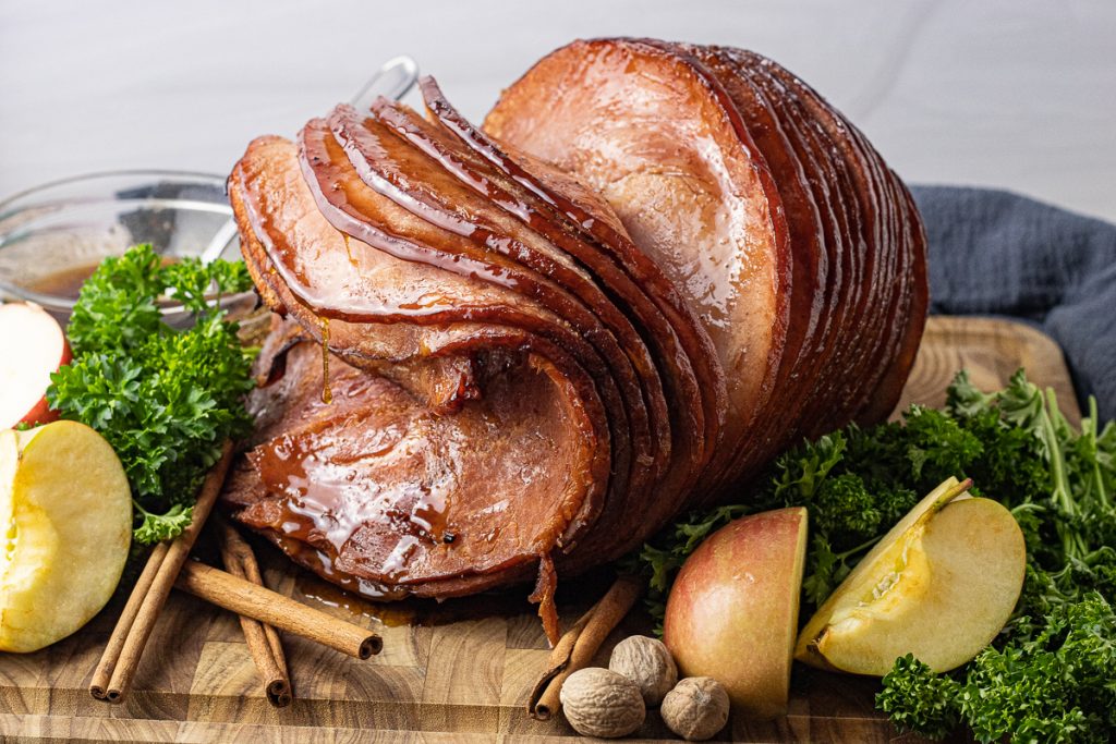 sliced ham on a wooden cutting board with dripping glaze