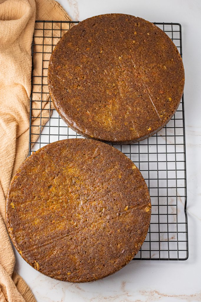 2 round carrot cakes on a wire cooling rack