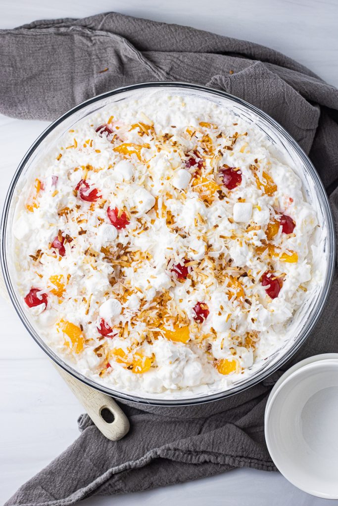fluffy fruit salad with small pasta, oranges, cherries and topped with toasted coconut