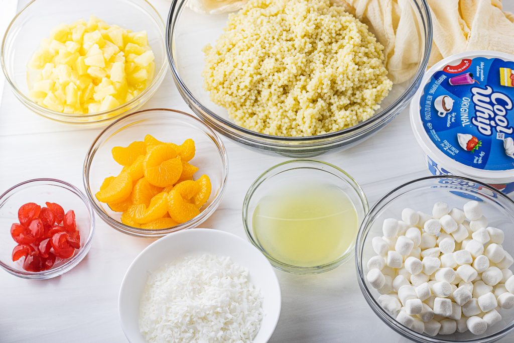 bowls filled with cherries, pineapple, mandarin oranges, pineapple juice, acini de pepe pasta and mini marshmallows