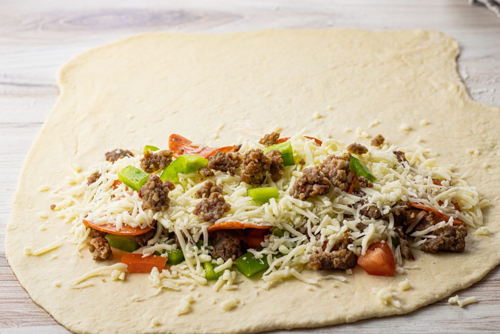 pizza dough rolled out into a circle with half filled with toppings