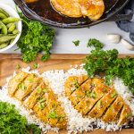 sliced chicken breasts over rice on a wooden platter