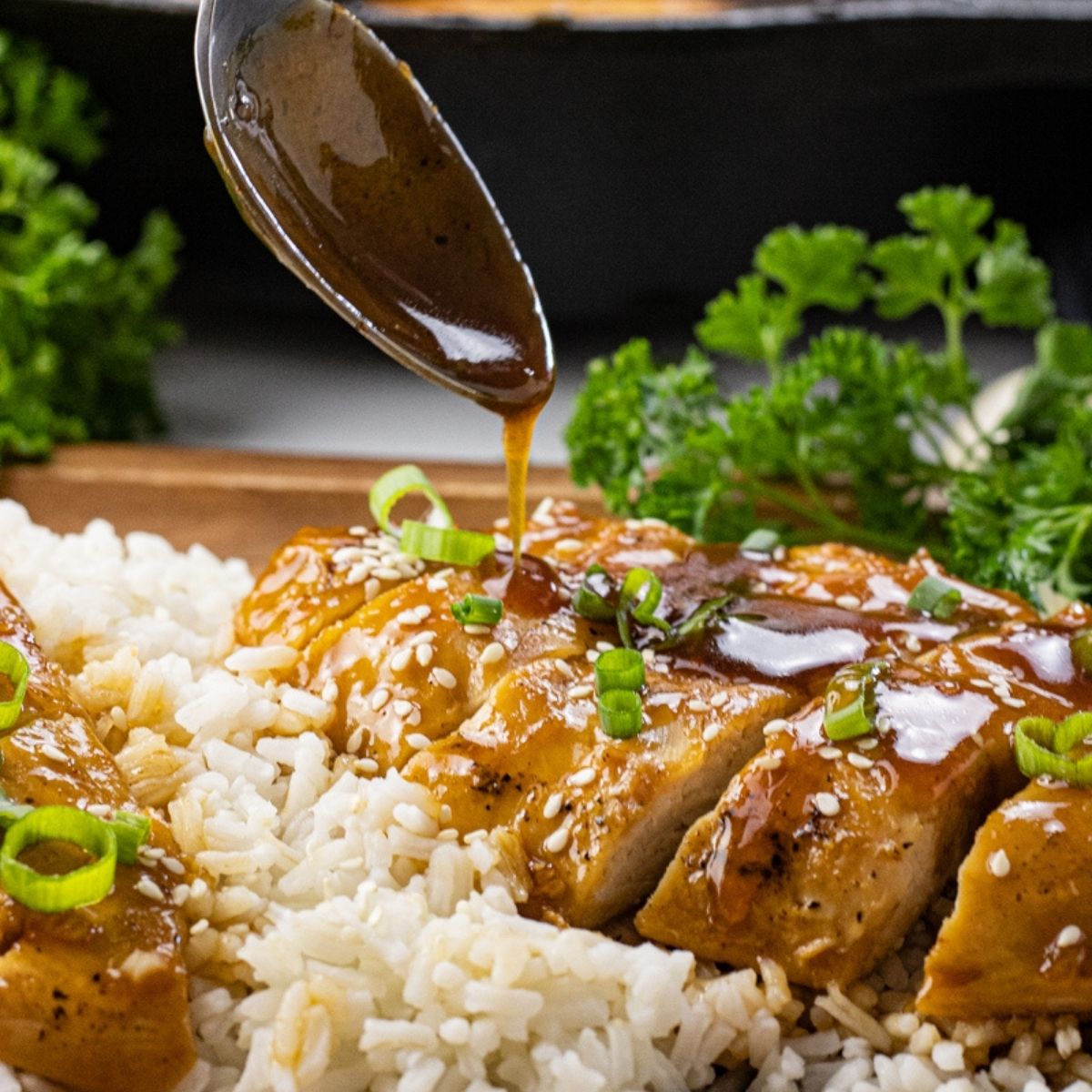 spoon drizzling sauce over sliced chicken
