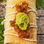 chimichanga topped with salsa and guacamole