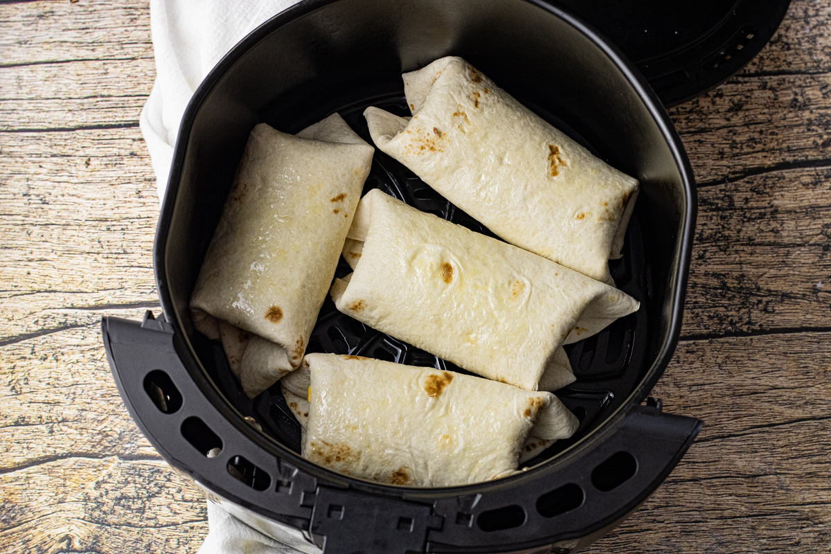 rolled up, stuffed tortillas in an air fryer basket