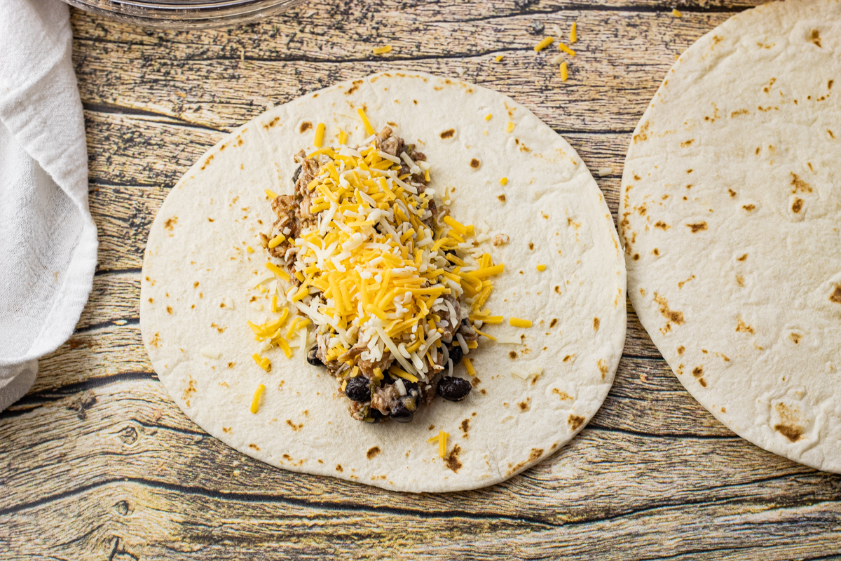 flat flour tortilla topped with shredded chicken and cheese