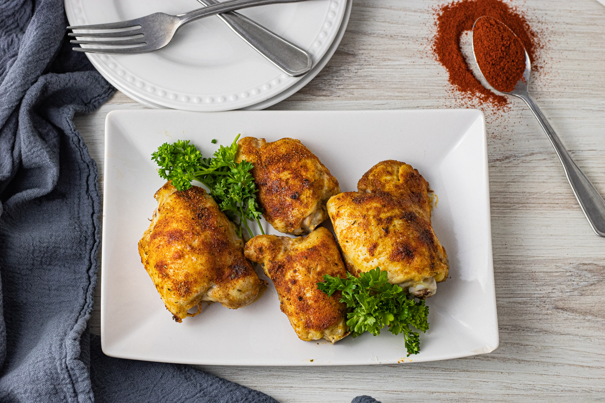 chicken thighs that have been cooked on a white plate with parsley