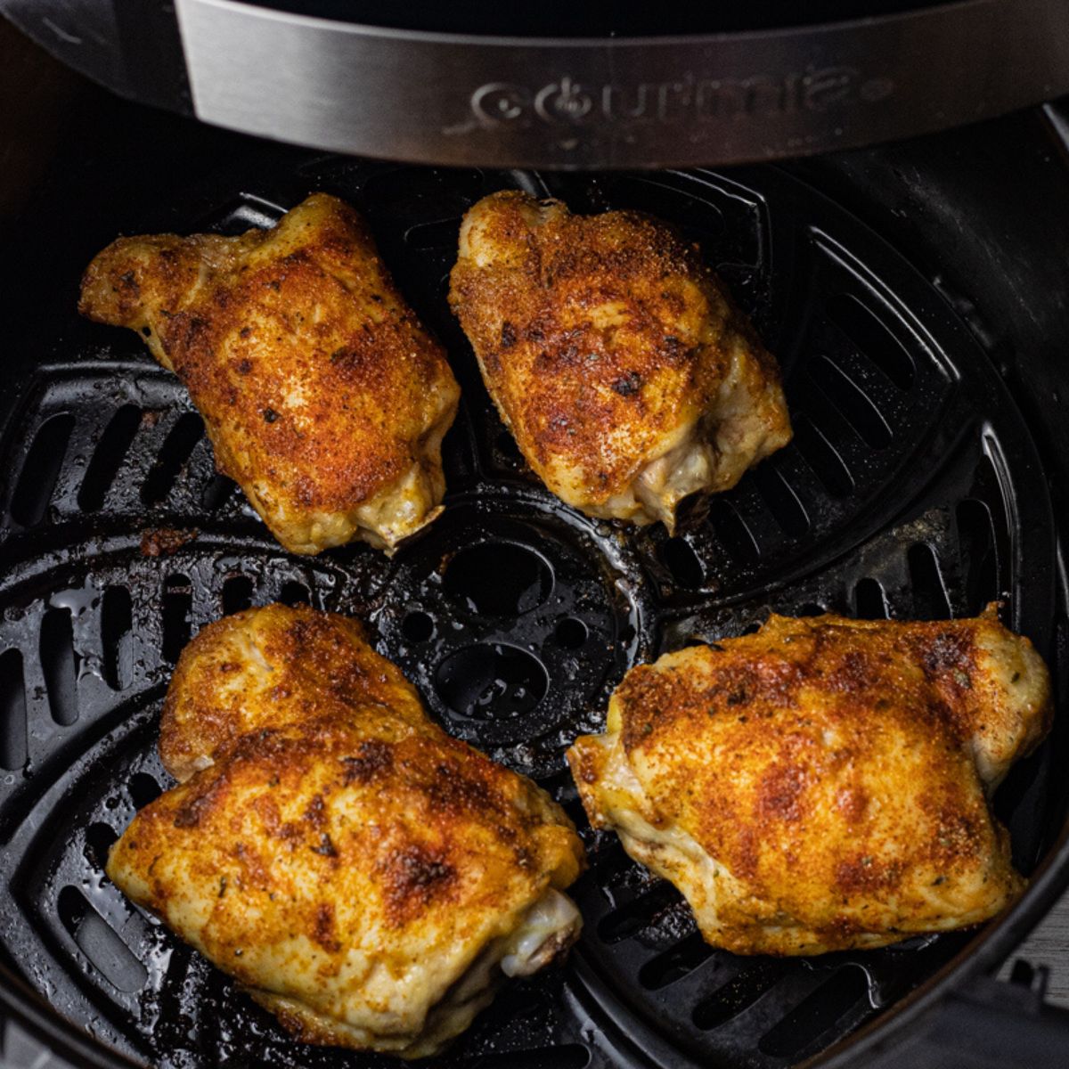 cooked chicken thighs in the basket of an air fryer