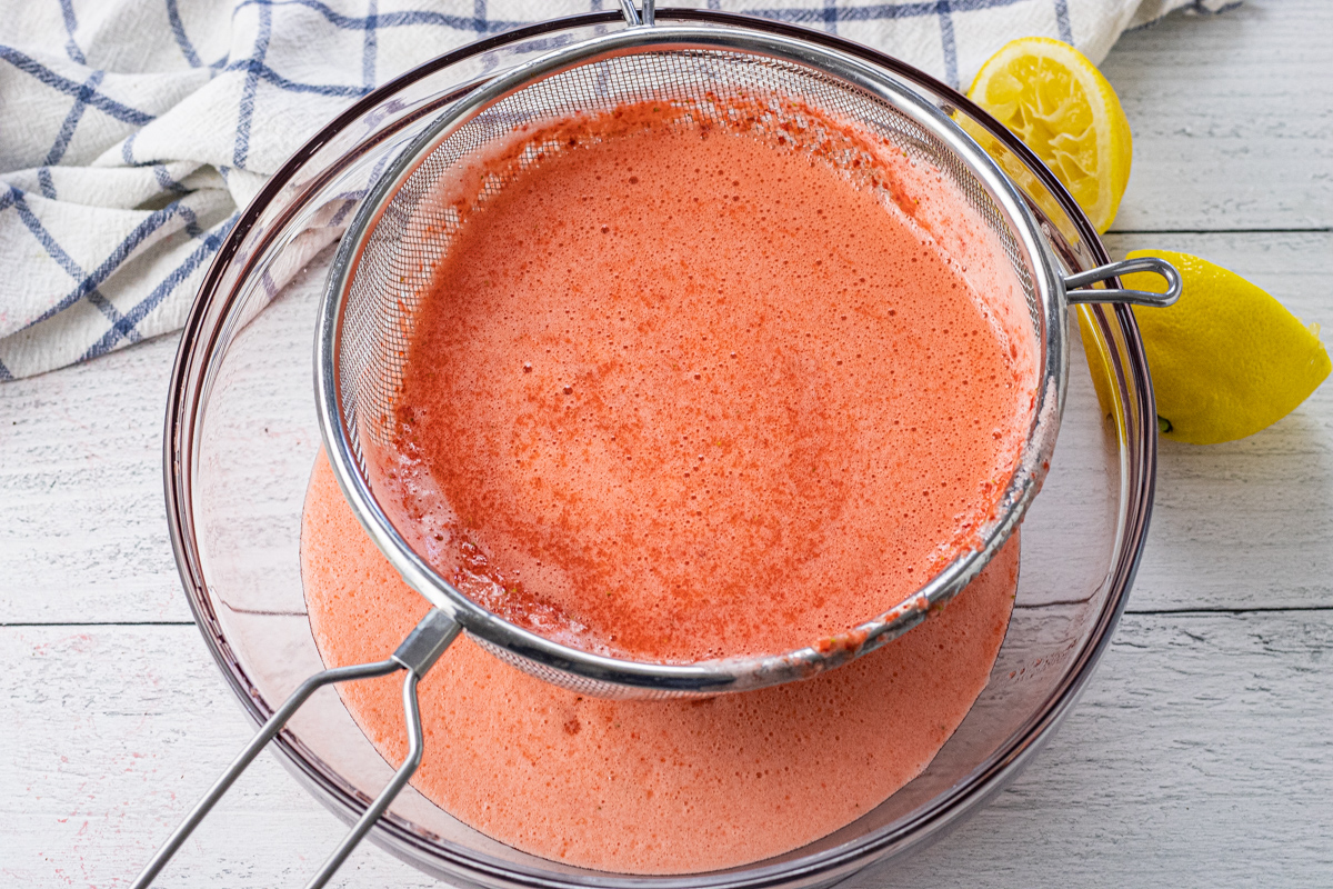 pour pureed strawberries through a strainer