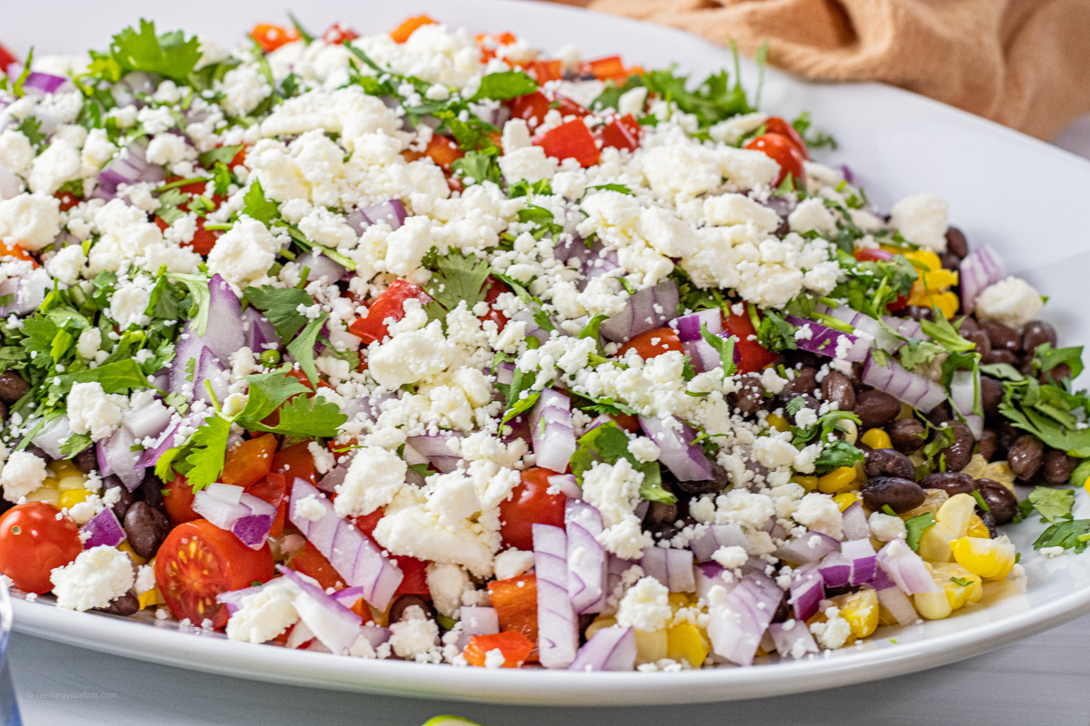 feta topping on a corn salad on a white platter