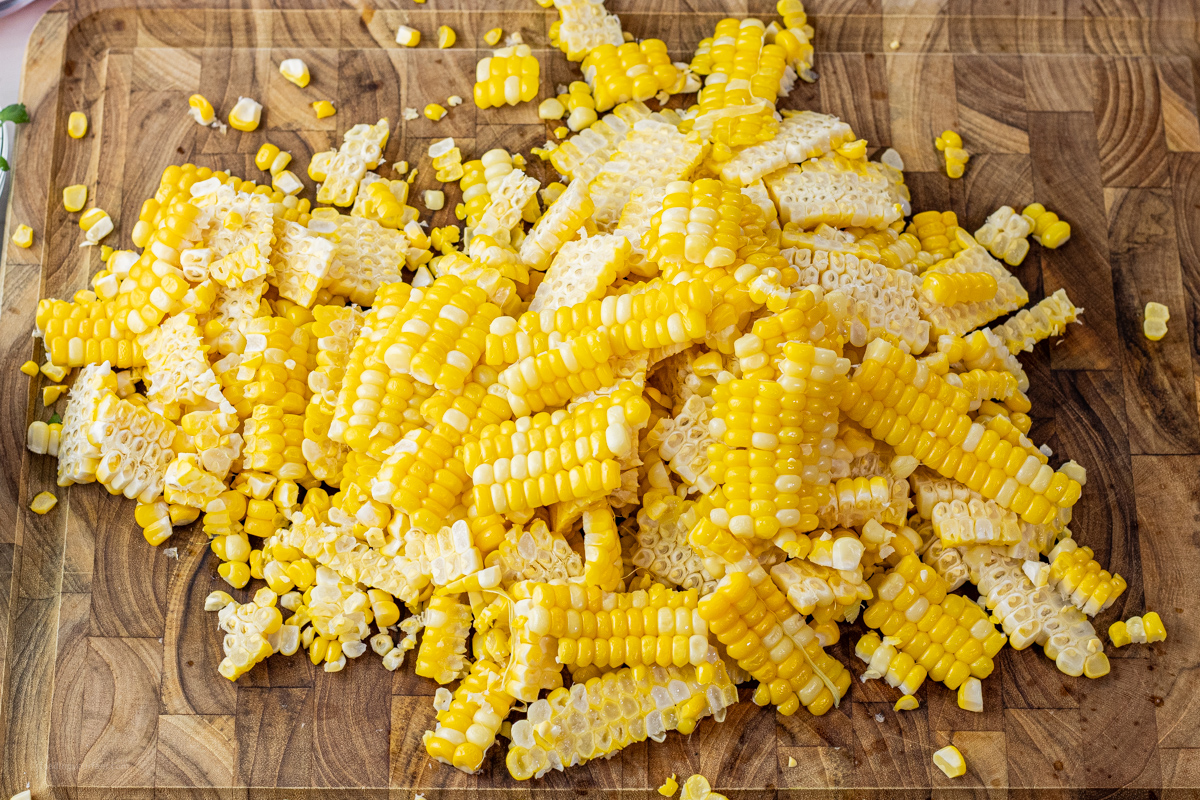 corn sliced off of the cob on a wooden cutting board
