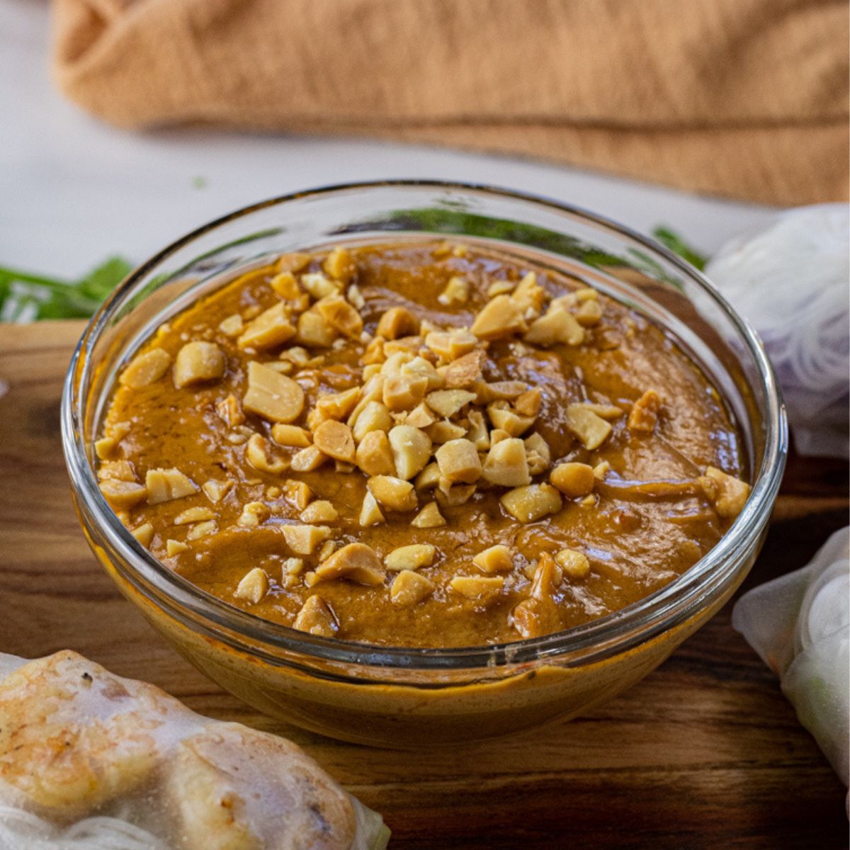 bowl of peanut sauce in a glass bowl topped with chopped peanuts