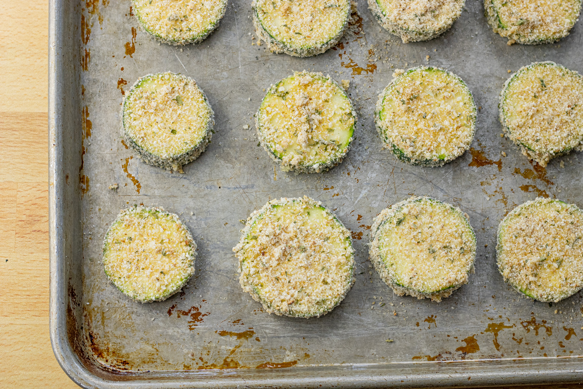 breaded zucchini rounds on a greased baking sheet