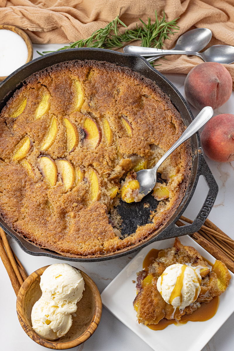 peach cobbler in a cast iron pan with some scooped out