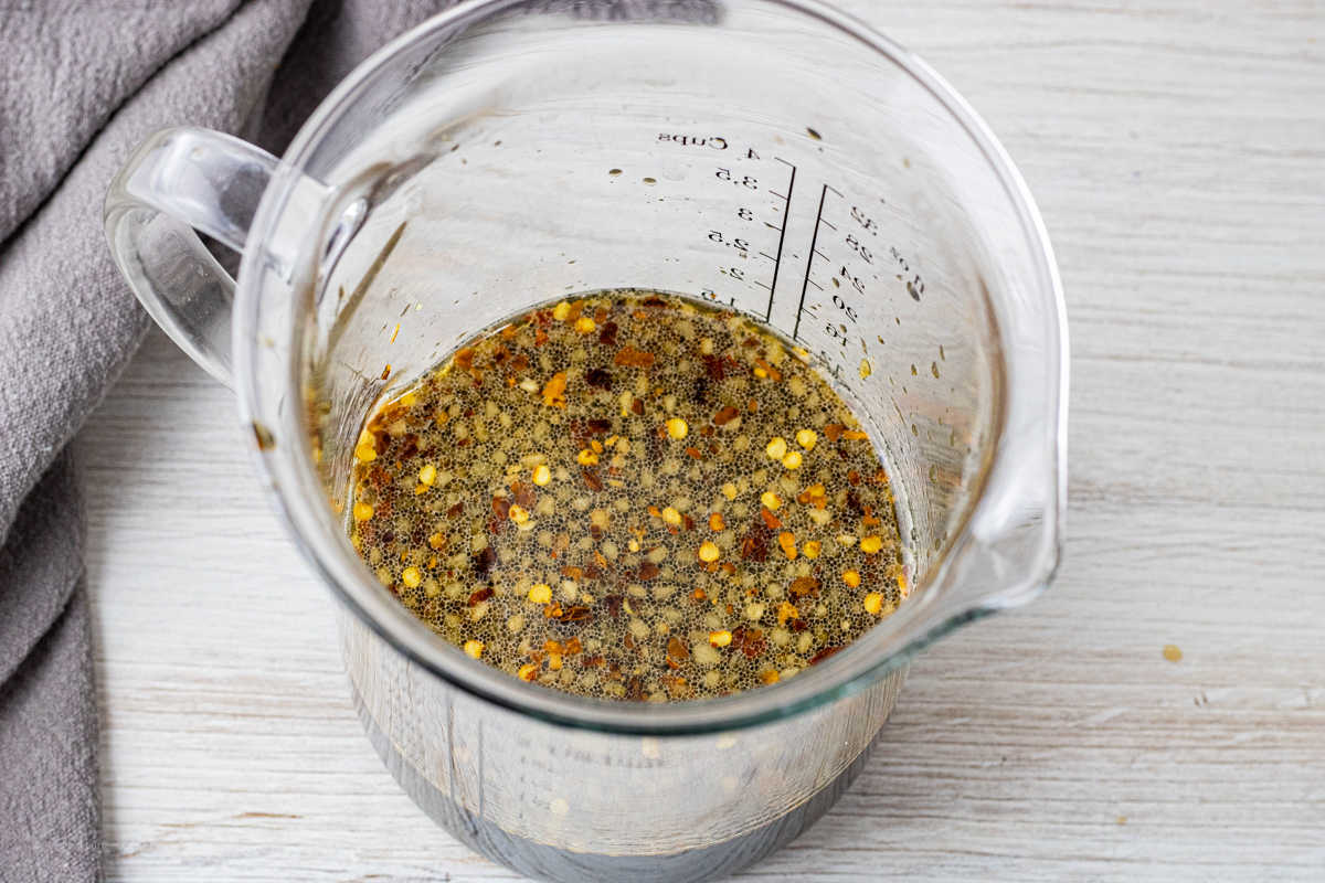 mixed teriyaki sauce with red pepper flakes in a large, glass measuring jar