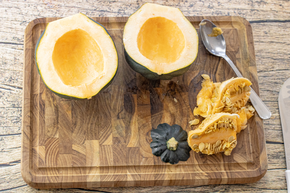 acorn squash sliced in half on a cutting board with the seeds removed.