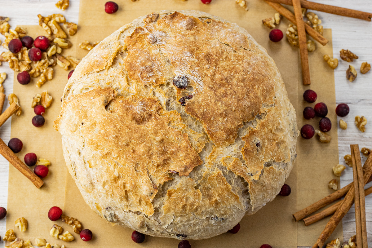 Whole round loaf of homemade cranberry walnut bread with a golden crust.