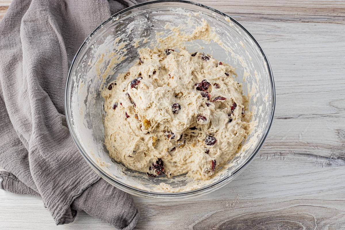 Cranberry walnut bread dough mixed and ready to rise in a glass bowl.
