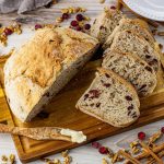 sliced cranberry walnut bread on a wooden cutting board