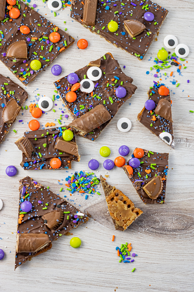 broken pieces of toffee covered pretzels coated with chocolate and halloween sprinkles and candies