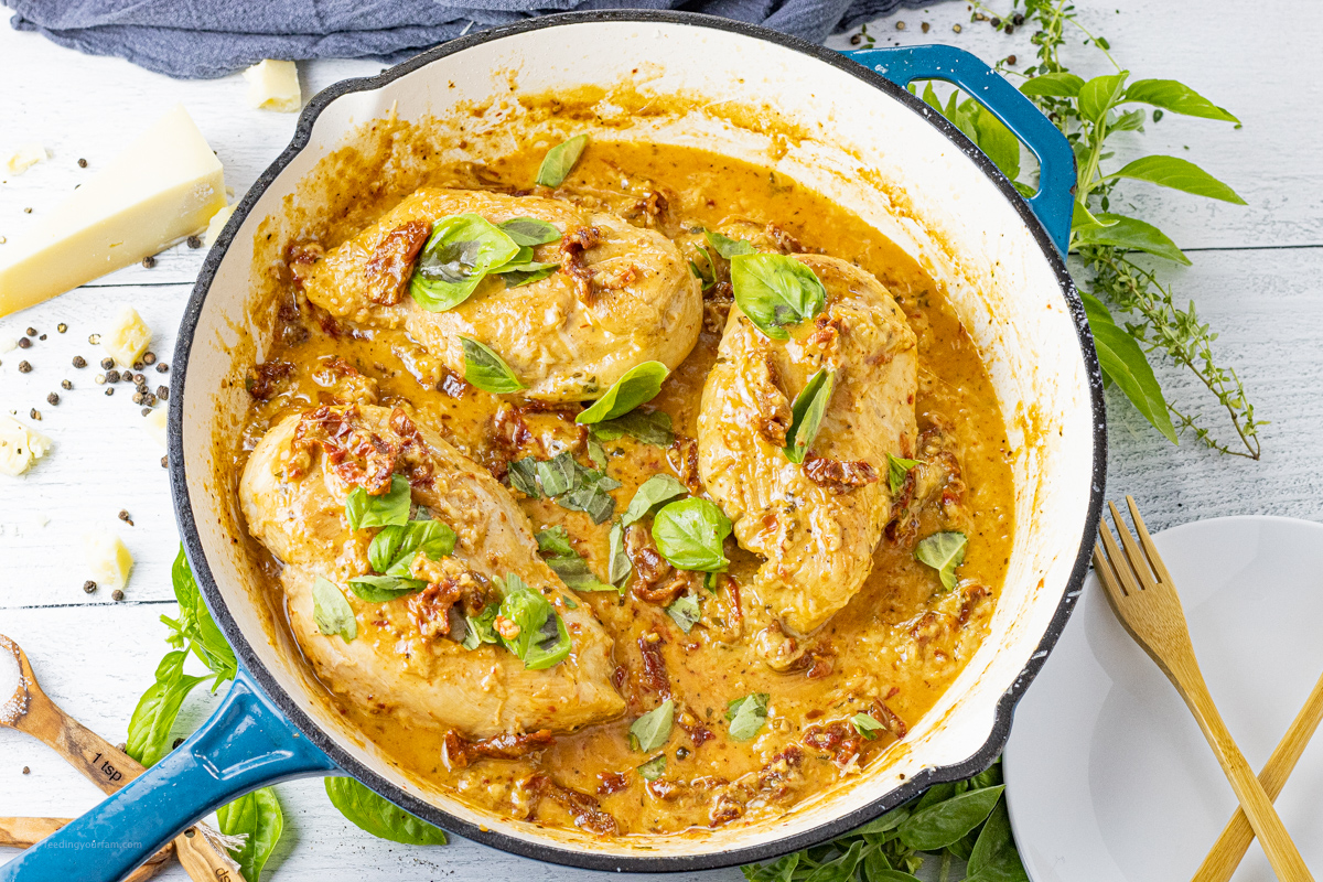 3 chicken breasts in a creamy tomato sauce topped with fresh basil in a pan