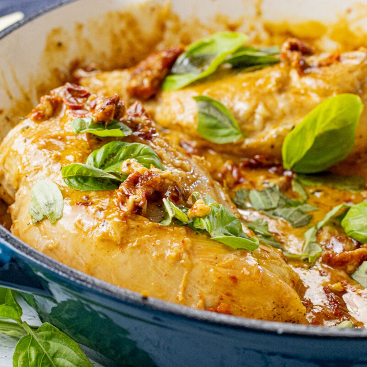 chicken in a creamy tomato sauce topped with fresh basil leaves
