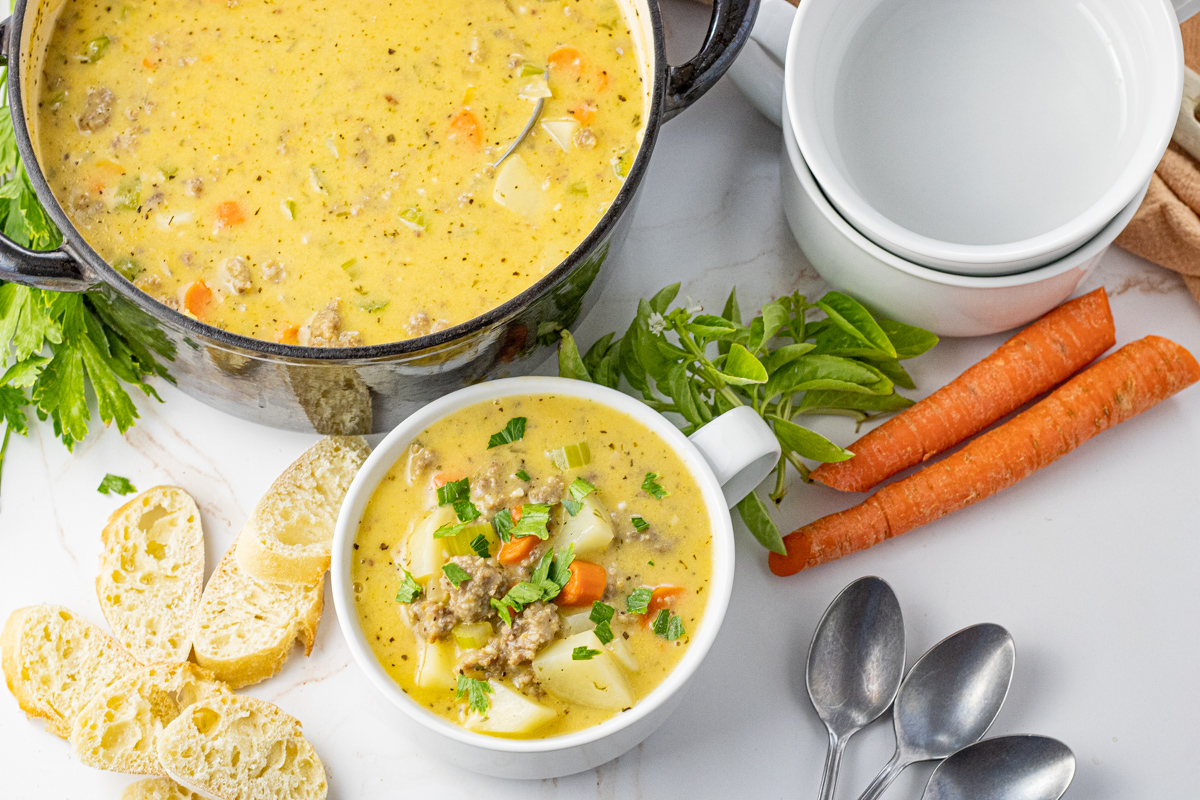 pot of cheesy sausage soup with a small white bowl filled with soup