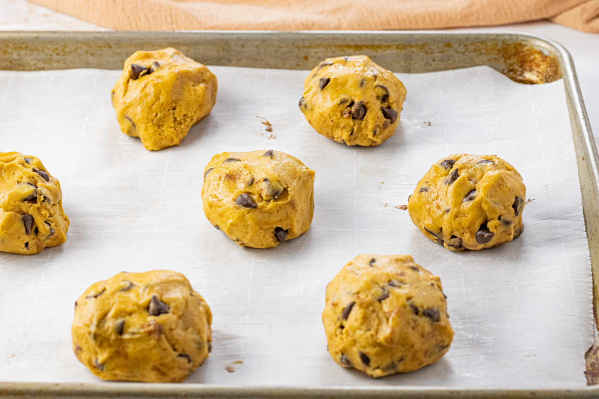 balls of pumpkin cookie dough on a parchment lined baking sheet
