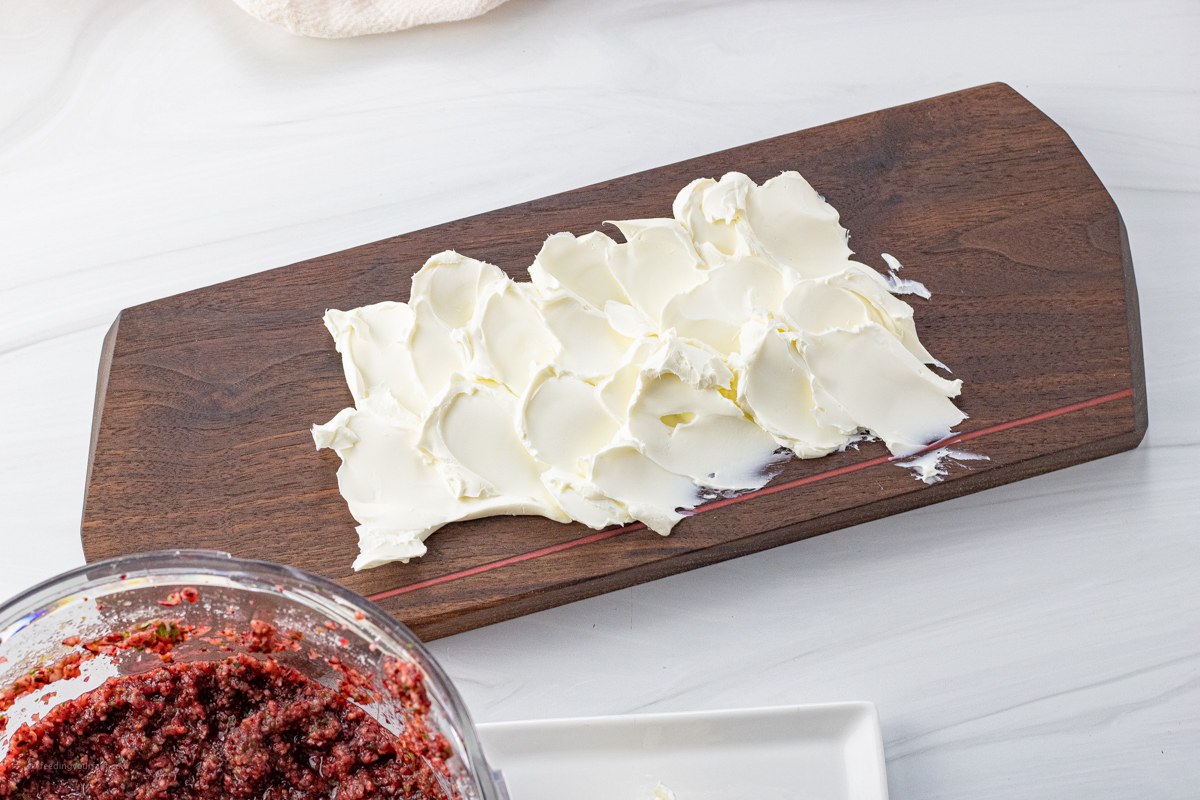 cream cheese spread onto a wooden serving platter