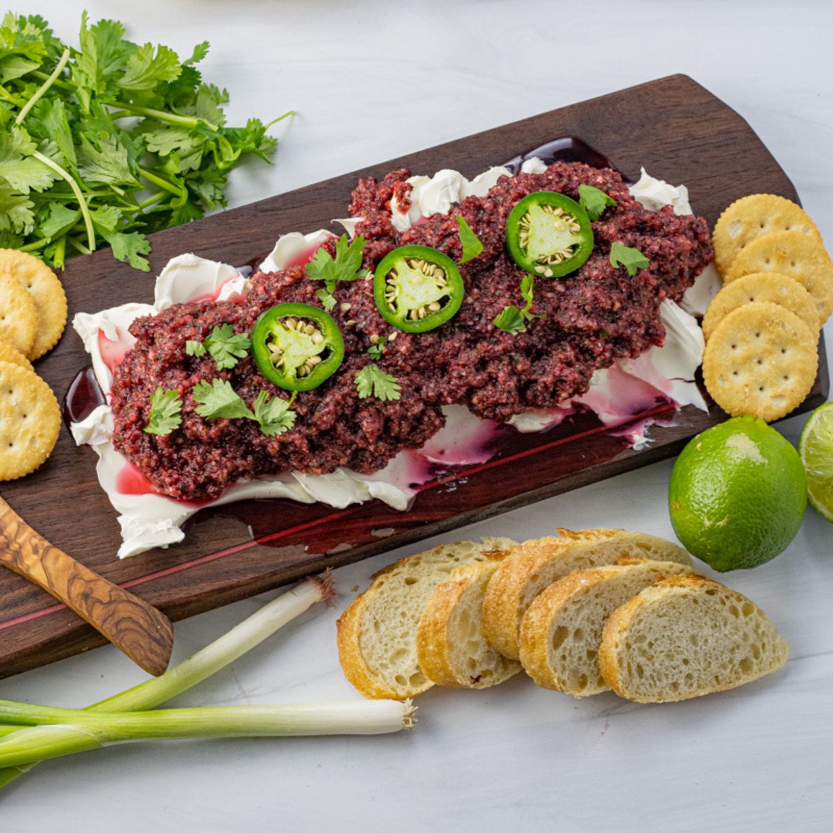 cream cheese topped with salsa made from cranberries on a wooden serving platter