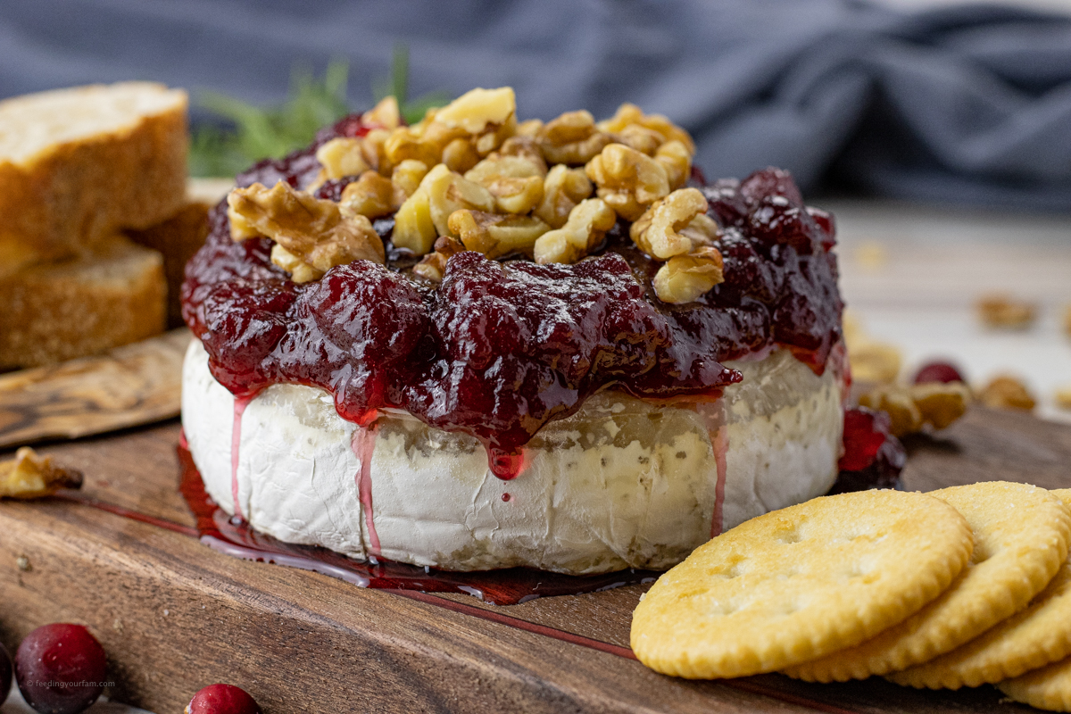 baked brie wheel topped with cranberries and chopped walnuts