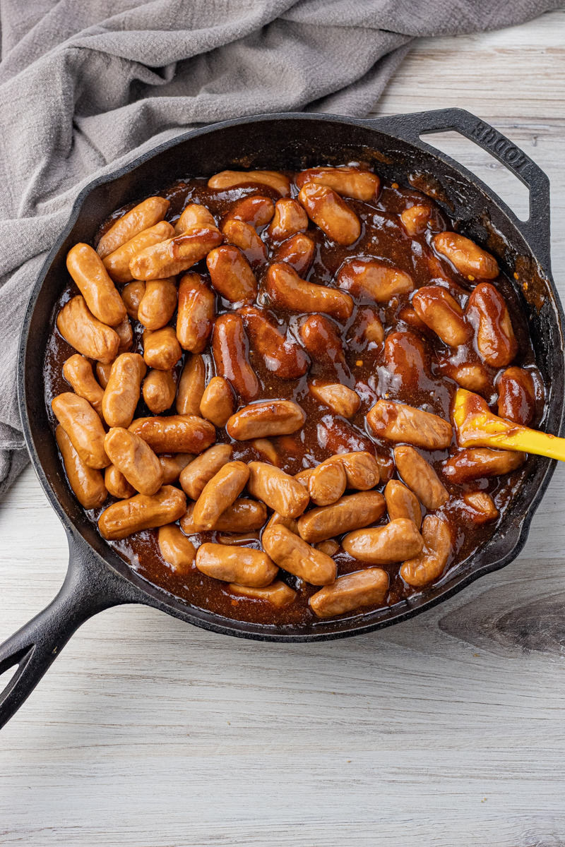 big cast iron pan filled with lil smokies and bbq sauce